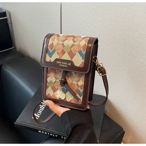 Detail of geometric pattern woven flap bag with brown leather trim and metallic charm