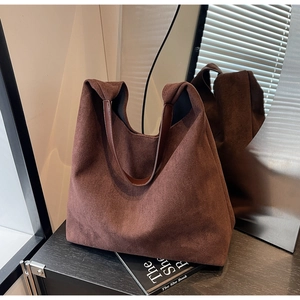 Detail shot of the matte suede texture and leather strap on a dark brown tote bag
