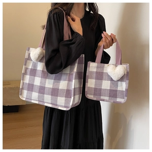 Detail of purple plaid tote bag set with heart charm shown on black dress