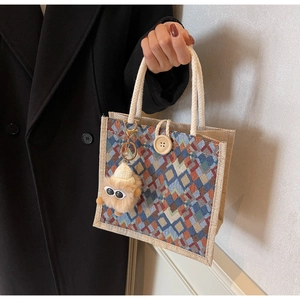 Detail of woven geometric handbag with large wooden button and plush monster charm
