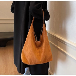 Detailed view of brown suede tote bag carried by a model wearing a stylish black coat