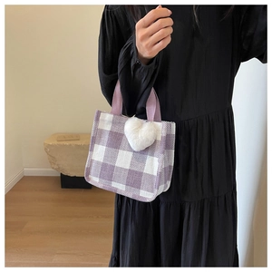 Detailed shot of purple checkered tote bag featuring a white plush heart charm accessory