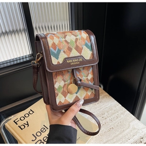 Detail of colorful geometric woven fabric and premium brown leather on a crossbody bag