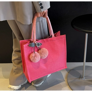 Close-up of pink linen tote bag with textured fabric and cherry plush charm detail
