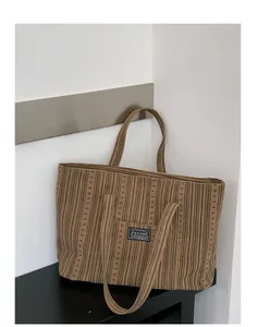 Detail of coffee striped canvas tote bag with fashion label and textured fabric finish