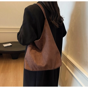 Brown suede hobo tote bag worn by a model in a minimalist elegant interior setting