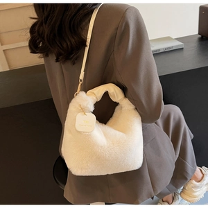 Detail of white plush shoulder bag with knotted handle and elegant gold logo tag