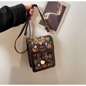 Detail of vintage geometric jacquard phone bag with brown leather trim and gold hardware