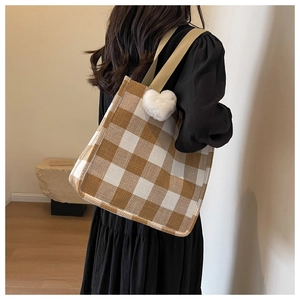 Detail of checkered tote bag with plush heart charm shown in casual everyday use