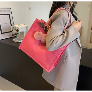 Pink linen tote bag with cherry plush charm shown on shoulder for high school students