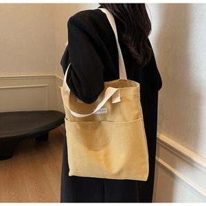 Detail of mustard yellow canvas tote bag featuring double front pockets and woven straps