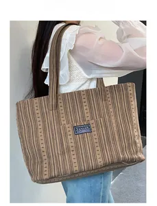 Detail view of large brown corduroy tote bag with fashion label on shoulder