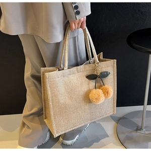 Detailed texture of large linen tote bag with cute plush cherry charm accessory
