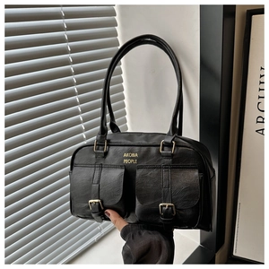 Close-up of black Boston bag with gold buckles and dual front flap pockets detail