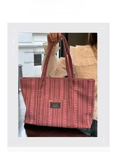 Detail of pink corduroy tote bag with black trim and fashion label for commute