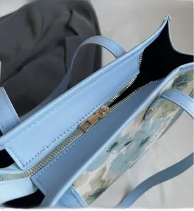 Détail du sac cabas floral bleu clair montrant la fermeture éclair dorée et le cuir fini