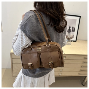 Detail of brown vintage shoulder bag featuring twin front pockets and metal buckles