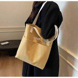 Detail of yellow canvas tote bag with large double front pockets and durable woven straps