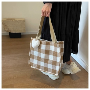 Close-up of brown checkered tote bag with heart charm and canvas handles for women