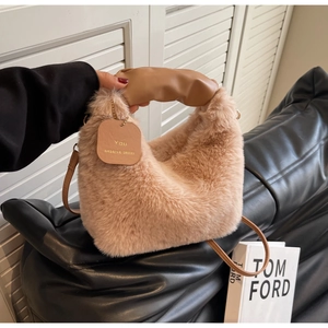 Detailed view of plush camel handbag with pleated texture and leather handle on sofa