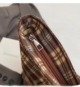 Détail macro de la fermeture éclair en métal argenté sur le sac cabas à carreaux marron