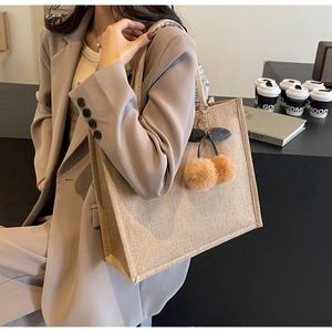 Linen tote bag with plush cherry pendant shown being worn by a model in a lifestyle setting