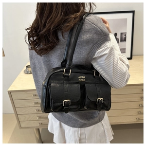 Detail of vintage black leather shoulder bag with gold buckles and front flap pockets