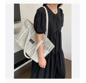 Detail of striped canvas tote bag with black geometric patterns and shoulder straps