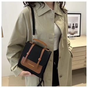 Close-up of black and brown crossbody bag with gold hardware and fashion inscription