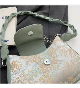 Close-up of sage green jacquard baguette bag with woven strap and metallic magnetic closure