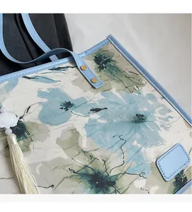 Détail du cabas floral montrant le tissu texturé et la bandoulière en cuir bleu