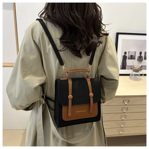 Detail of a two-tone canvas backpack with brown leather accents shown in lifestyle setting