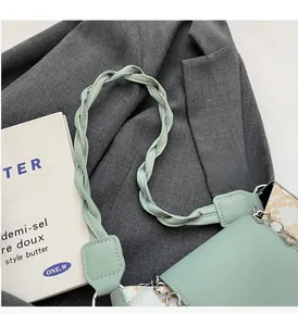 Detail of mint green leather baguette bag with woven handle and silver chain strap