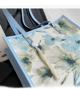 Détail d'un cabas floral avec bordure bleu clair et élégant pompon décoratif