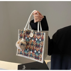 Detail of geometric pattern canvas handbag with rope handle and plush eye pendant