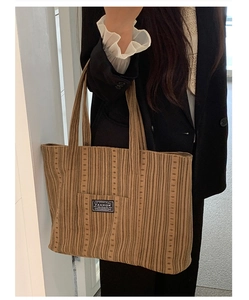 Detailed close-up of brown striped tote bag with fashion label and textured fabric