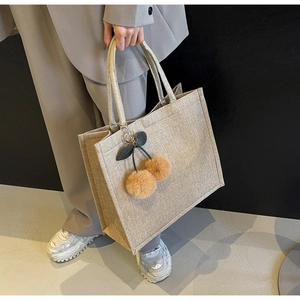 Detailed texture of the khaki linen tote bag with a cute cherry faux fur ball keychain