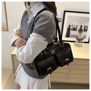 Macro detail of black leather Boston bag with gold buckles and front pockets