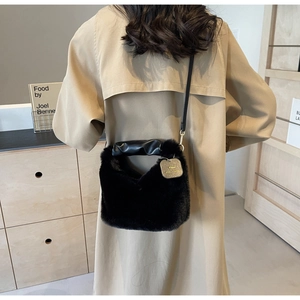 Detail of black plush handbag with ruched handle and shoulder strap in a stylish room