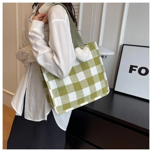 Detail of green checkerboard canvas tote bag with white plush heart charm and wide strap