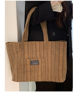 Detail of brown corduroy tote bag showing vertical stripes and fashion label patch
