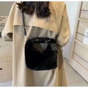 Detail of black plush handbag with ruched leather handle and gold metal connectors