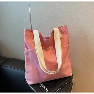 Detailed shot of pink canvas tote bag showing side pocket and white woven shoulder strap