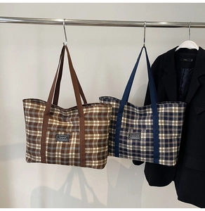 Détail de grands sacs fourre-tout à carreaux marron et bleu marine avec patch de mode