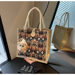 Detail of colorful diamond pattern linen handbag with rope handle and plush monster charm