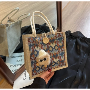 Detail of linen tote with woven diamond pattern, wooden button and plush monster charm