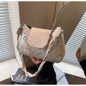 Detail of floral embroidery and chain strap on a chic beige faux leather baguette bag