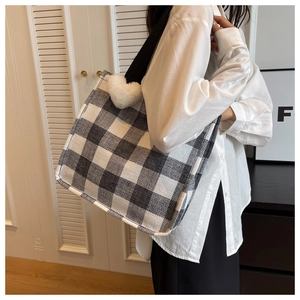Detailed shot of large checkerboard tote bag with white plush heart charm on the strap