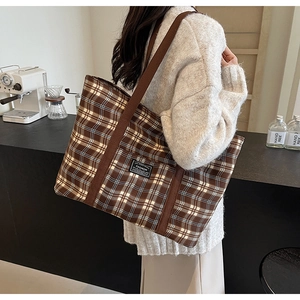 Détail d'un grand sac cabas en toile à carreaux marron avec de larges bandoulières