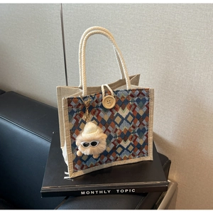 Detail view of woven geometric tote bag with rope handle and wooden button closure